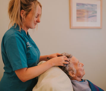 Female complementary therapist performing reiki on a female patient by touching her head