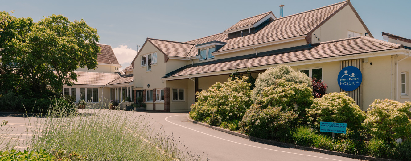 Outside the front of the North Devon Hospice building, in the sunshine with plants in the foreground