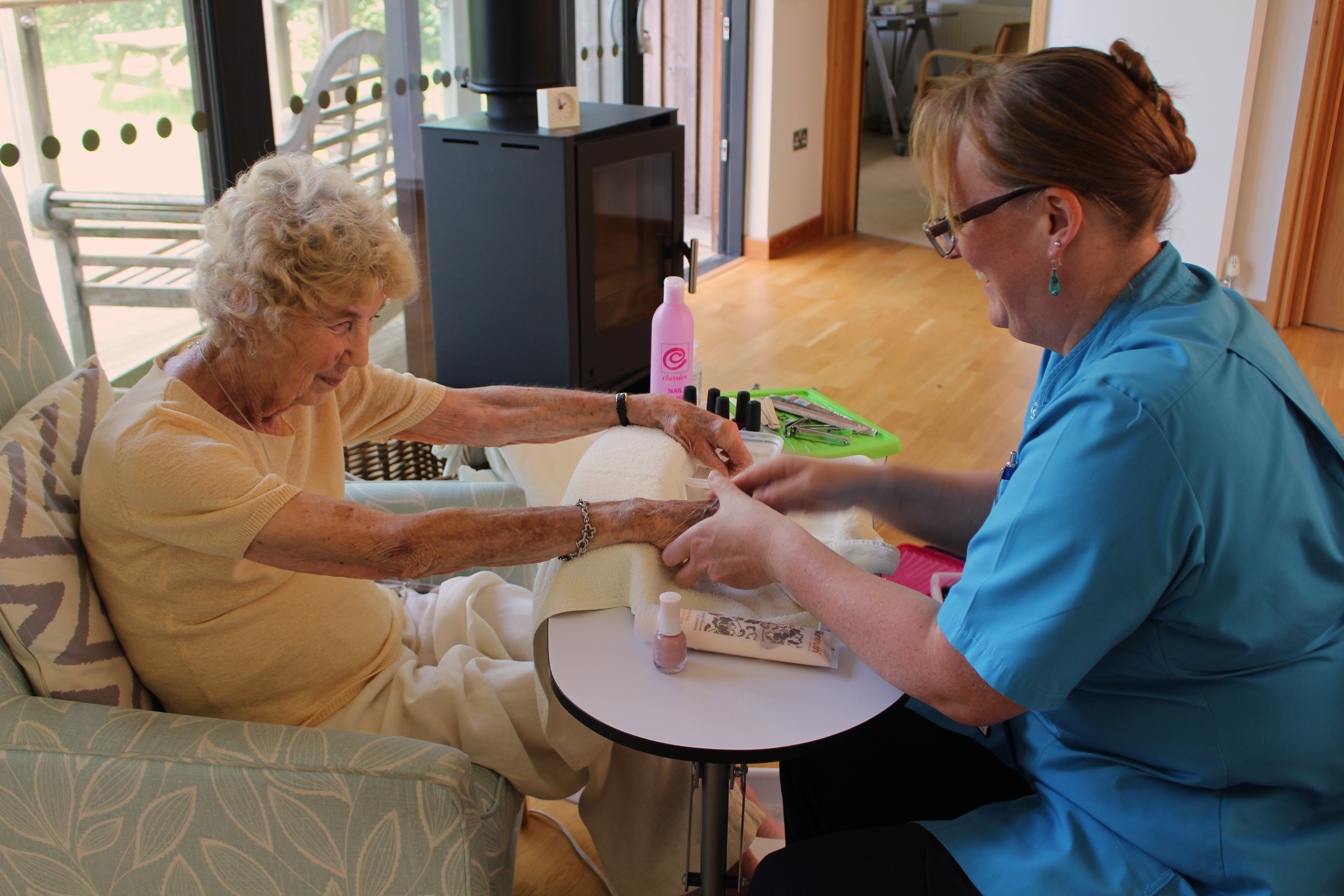 Female patient receiving a hand massage from a female complementary therapist on a small, white table